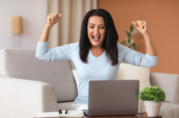Excited mature woman screaming yes using laptop - Fotoğraf, Görsel