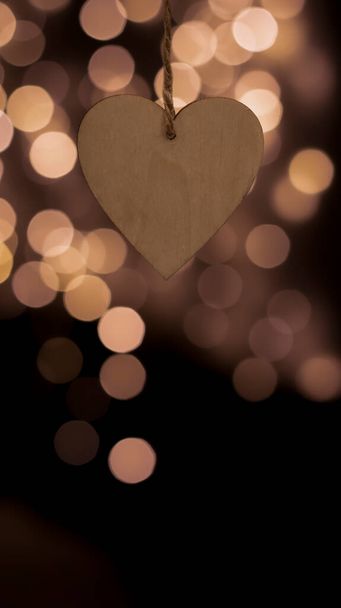Wooden Christmas tree toy in the shape of a heart on a blurred bokeh background. Close-up, blurred background. Festive New Year background. Festive postcard, night view. - Fotó, kép