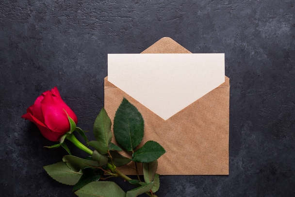 Red rose flower and envelope on black stone background Copy space Flat lay - Foto, afbeelding