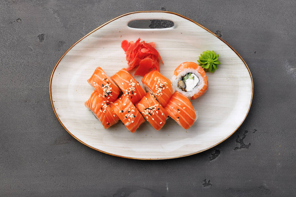 Top view of Philadelphia sushi roll on plate on black table - Фото, изображение