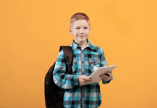 Smart schoolboy with backpack holding digital tablet - Foto, Bild