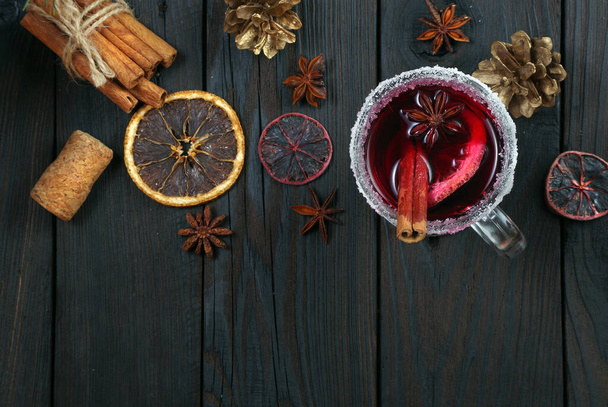 forralt bor, fűszerek és száraz citrusfélék csészéi egy fából készült asztalon. melegítő karácsonyi ital  - Fotó, kép