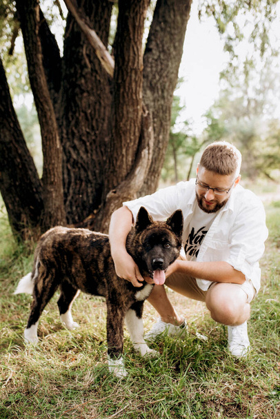 Американская собака Акита для прогулки с парнем и девушкой на зеленой прерии - Фото, изображение