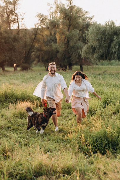 Chien Akita américain pour une promenade avec un gars et une fille dans la prairie verte - Photo, image