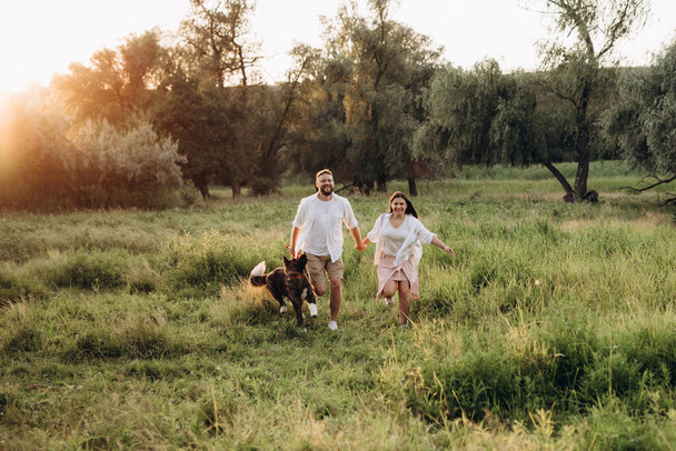 American Akita cane per una passeggiata con un ragazzo e una ragazza sulla prateria verde - Foto, immagini