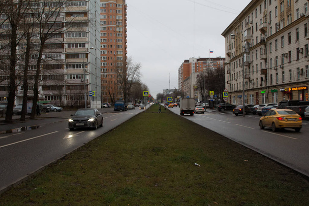 Moscow, Russia, November 30, 2020: view of the street of Zoya and Alexander Kosmodemyanskikh, along which cars drive, from the dividing green strip in the center - Zdjęcie, obraz
