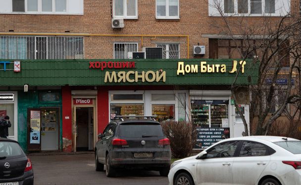 Moscow, Russia, November 30, 2020: Parked cars stand in front of shops on Pryanishnikova street. Inscriptions on shops from left to right: "Good Meat, House of Life" - Photo, Image