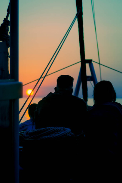 Pareja en un velero Siluetted Against Vibrant Sunrise frente a la costa de la isla de Mallorca en el mar Mediterráneo - Foto, Imagen