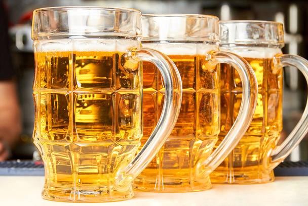 Tres vasos de cerveza espumosa fresca en el mostrador del bar - Foto, imagen