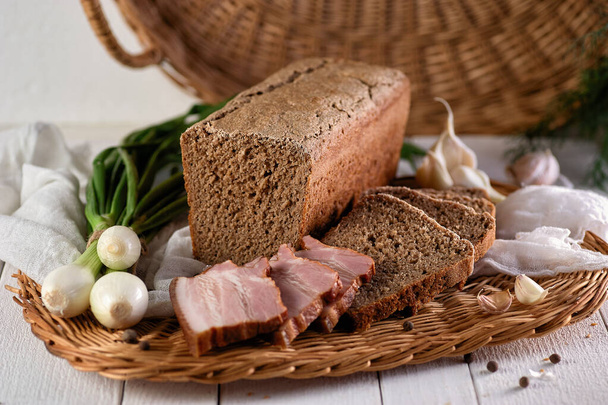 自家製のライ麦パンは、新鮮な焼きたての香りと肉製品と玉ねぎをウィッカープレート上に - 写真・画像