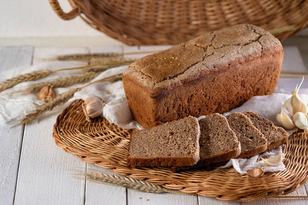 Kahvaltı için ev yapımı çavdar ekmeği hasır bir tabakta taze pişmiş aroma. - Fotoğraf, Görsel