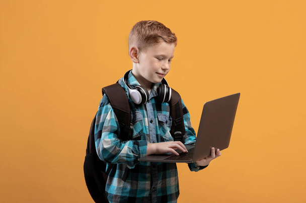 Smart schooljongen met rugzak en headset met laptop - Foto, afbeelding