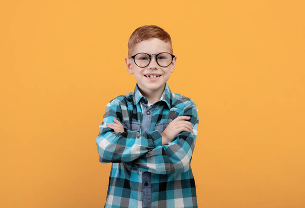 Niño feliz en gafas con los brazos cruzados en amarillo - Foto, imagen
