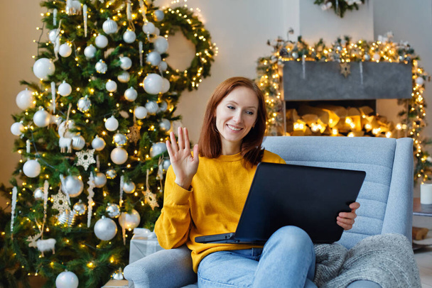 Egy fiatal nő távolról kommunikál egy számítógéppel. Újévi üdvözlet az interneten keresztül. Karácsonyi hangulat - Fotó, kép