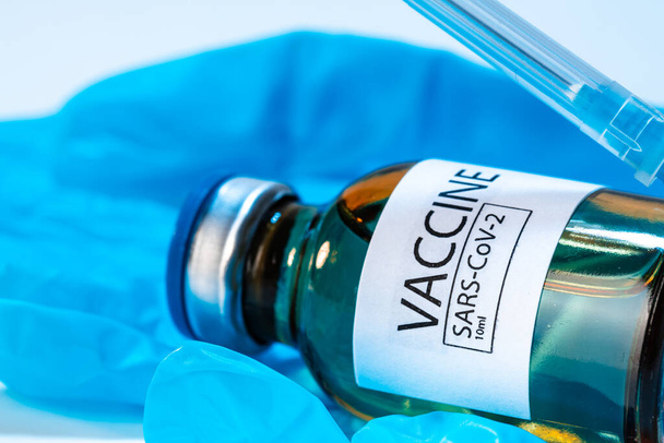 Doctor hands in blue gloves holding Sars-cov-2 vaccine vial - Φωτογραφία, εικόνα