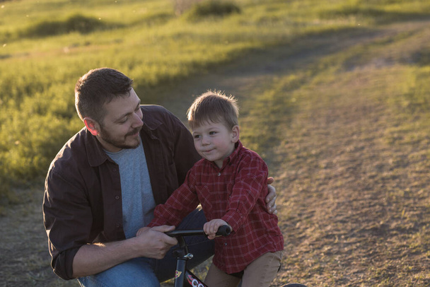 Glücklicher junger Vater mit seinem kleinen Sohn, der Spaß im Freien hat. Glück und Harmonie im Familienleben. - Foto, Bild