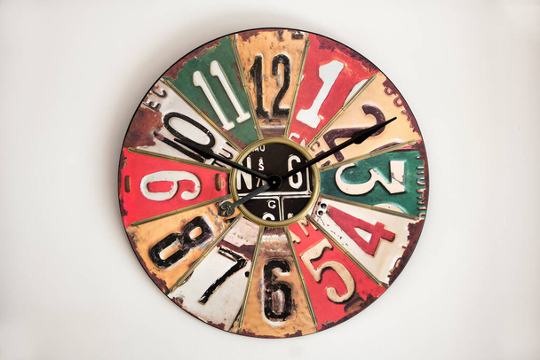 L'orologio con quadrante in metallo vintage su parete bianca, riferito al design degli anni '30-' 50, con cifre e settori di diversi colori - Foto, immagini