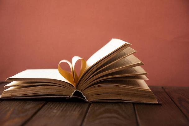 Old open hardback book, page decorate into a heart shape for love in Valentine 's. любовь с открытым сердцем книги. - Фото, изображение