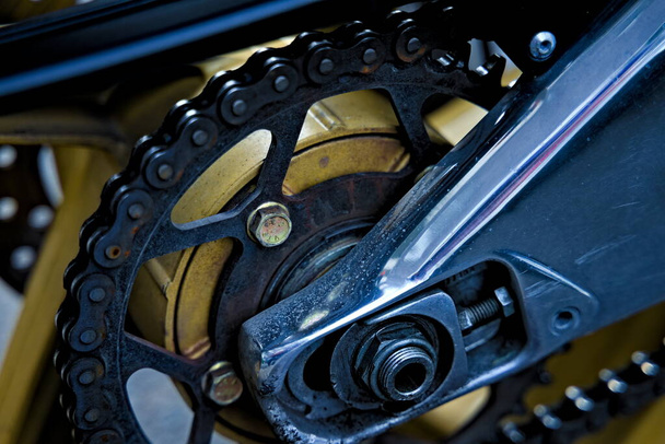 Close up of the chain and back wheel of an older motorcycle. . High quality photo - Photo, Image