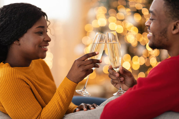 Улыбающаяся молодая африканская пара американских стаканов с шампанским в гостиной - Фото, изображение