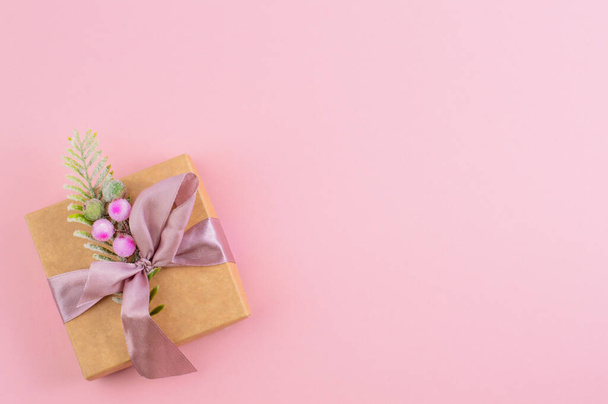Su uno sfondo rosa chiaro con un posto per scrivere il testo, c'è una bella scatola con un regalo. - Foto, immagini