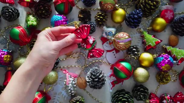 Vidrio, plástico, decoraciones de árboles de Navidad en la mesa. Manos de mujer. Primer plano - Metraje, vídeo