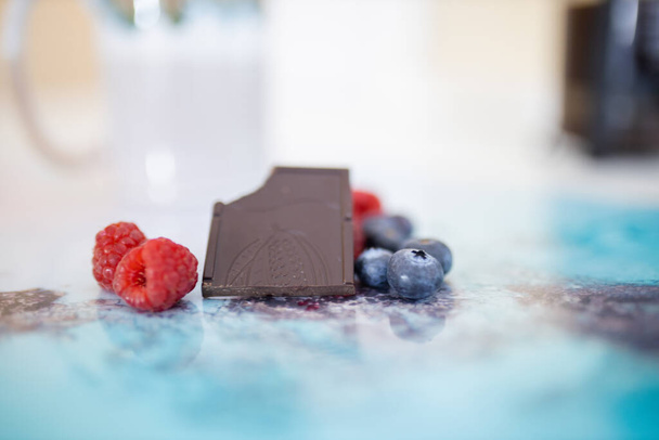 Morso barretta di cioccolato e bacche su una tovaglietta colorata - Foto, immagini
