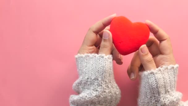  ženy ruka drží červené srdce na růžovém pozadí  - Záběry, video