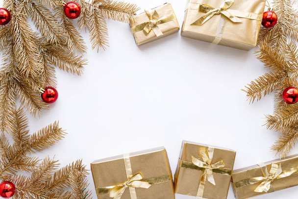 Białe Boże Narodzenie lub nowe tło lat, gładka kompozycja złote prezenty świąteczne i gałązki złotej jodły z zabawek Bożego Narodzenia, Flatlay, puste miejsce na powitanie text.christmas koncepcja. - Zdjęcie, obraz