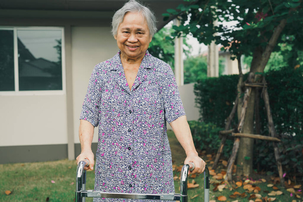 Азиатская пожилая или пожилая старуха пациентка ходить с ходунком в парке дома, здоровый сильный медицинский концепт - Фото, изображение