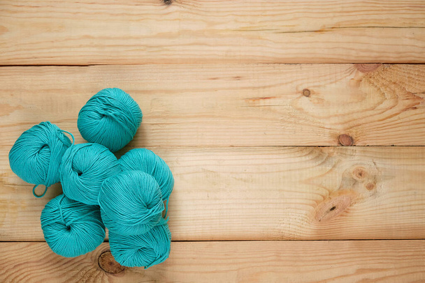 Balls of colored natural yarn in turquoise shades on a wooden background. Selective focus. Space for text - Photo, Image