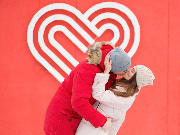 Молодая пара целуется в городе рядом с большим сердцем на стене. День Святого Валентина - Фото, изображение