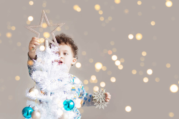 Menino em pijamas decorando árvore de Natal branca - Foto, Imagem