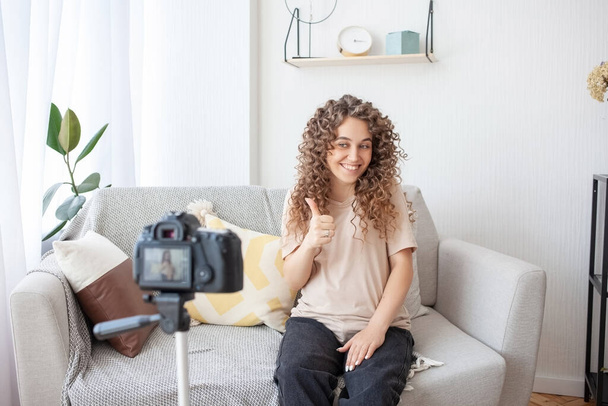 Happy future mother creates a new video for her channel, sits on sofa and invites everyone to put comment. Pregnancy, video blogging and technology concept. - Foto, Imagem