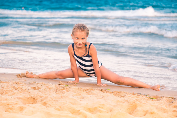Beautiful little girl excercising on the beach - Photo, Image