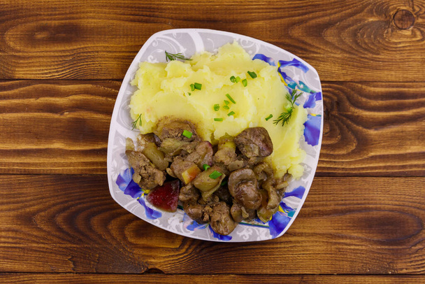 Purê de batatas com fígado de frango cozido com maçã e cebola na mesa de madeira
 - Foto, Imagem