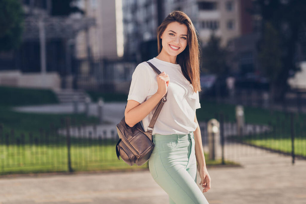 Photo portrait of young woman holding brown backpack posing outdoors - Zdjęcie, obraz