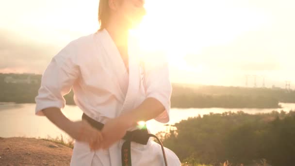Traducción: Kyokushinkai. mujer joven kimono blanco demuestra la técnica del karate contra la naturaleza del telón de fondo - Metraje, vídeo