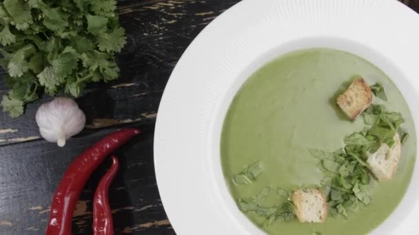 Piatto di gustosa zuppa di crema di spinaci sul tavolo, vista dall'alto - Filmati, video