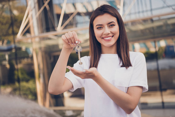 Photo portrait of girl holding presenting keychain outside - Photo, image