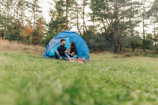 Красивая пара разговаривает, сидя у входа в палатку - Фото, изображение