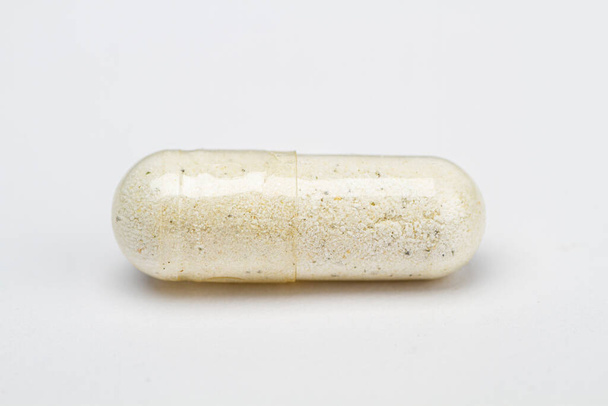 Primer plano de una píldora transparente llena de ingrediente blanco - Foto, Imagen