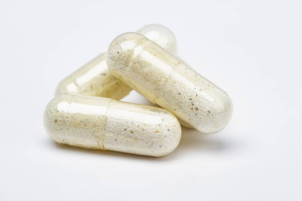 három átlátszó tabletta, fehér és fekete specifikációjú összetevőkkel, fehér háttérrel - Fotó, kép