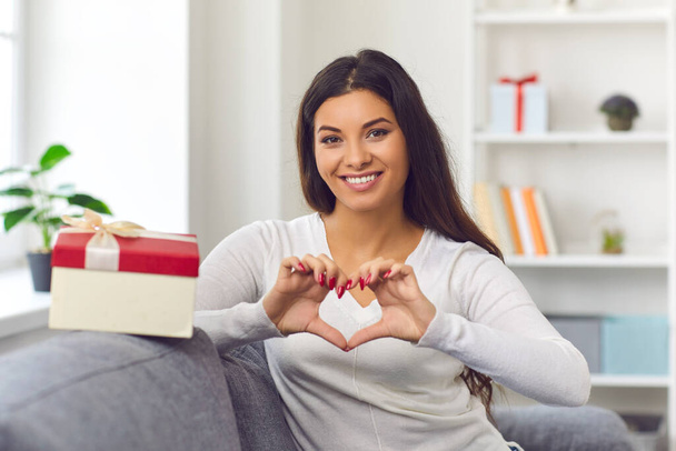 Happy young woman in love doing heart-shaped gesture and saying thank you for Valentine present - Foto, imagen