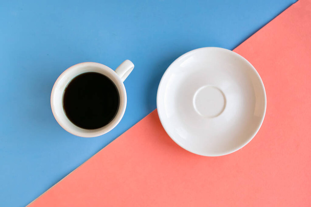 чашка кофе и пустая тарелка на цветном геометрическом фоне, минимальная концепция - Фото, изображение
