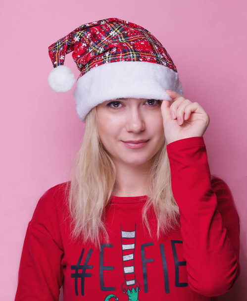 Portrét krásné ženy v červeném klobouku Santa Claus izolované na růžovém pozadí. Krásná dívka vypadá šťastně a vzrušeně. Veselé Vánoce a Nový rok plné zábavy. panorama. kopírovat prostor. nápis - Fotografie, Obrázek