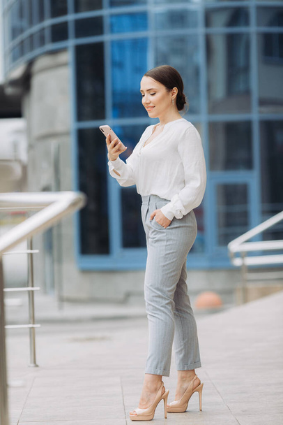 Business Woman Walking on the Street in the Business District, Checks Her Smartphone. - Foto, Imagen