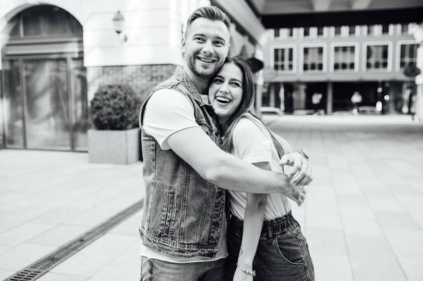 Fashion outdoor romantic portrait of beautiful young couple in love and hugs on the street. - Фото, изображение