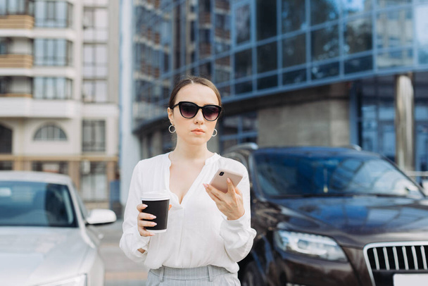 Una mujer de negocios caminando por la calle en un distrito de negocios hablando por teléfono. - Foto, Imagen
