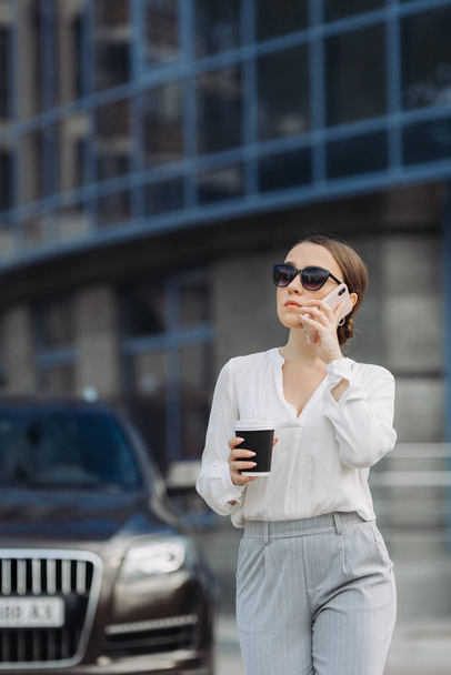 Деловая женщина, идущая по улице в деловом районе, разговаривает по телефону. - Фото, изображение